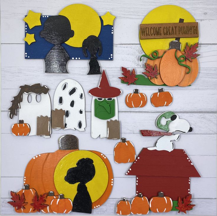 a group of paper cut outs sitting on top of a white wooden table next to pumpkins