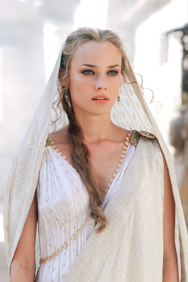 a woman dressed in white with a veil on her head and braids around her neck