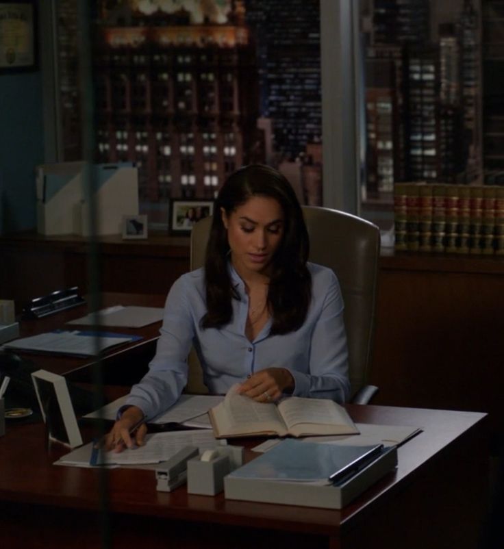 a woman sitting at a desk with an open book