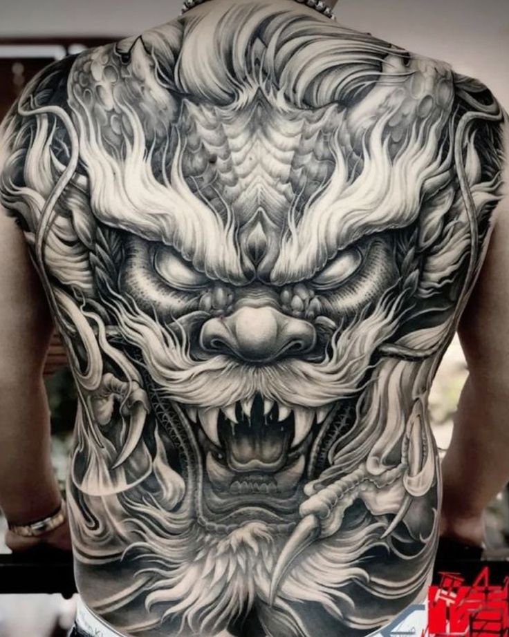 the back of a man's body with tattoos on it and an image of a dragon