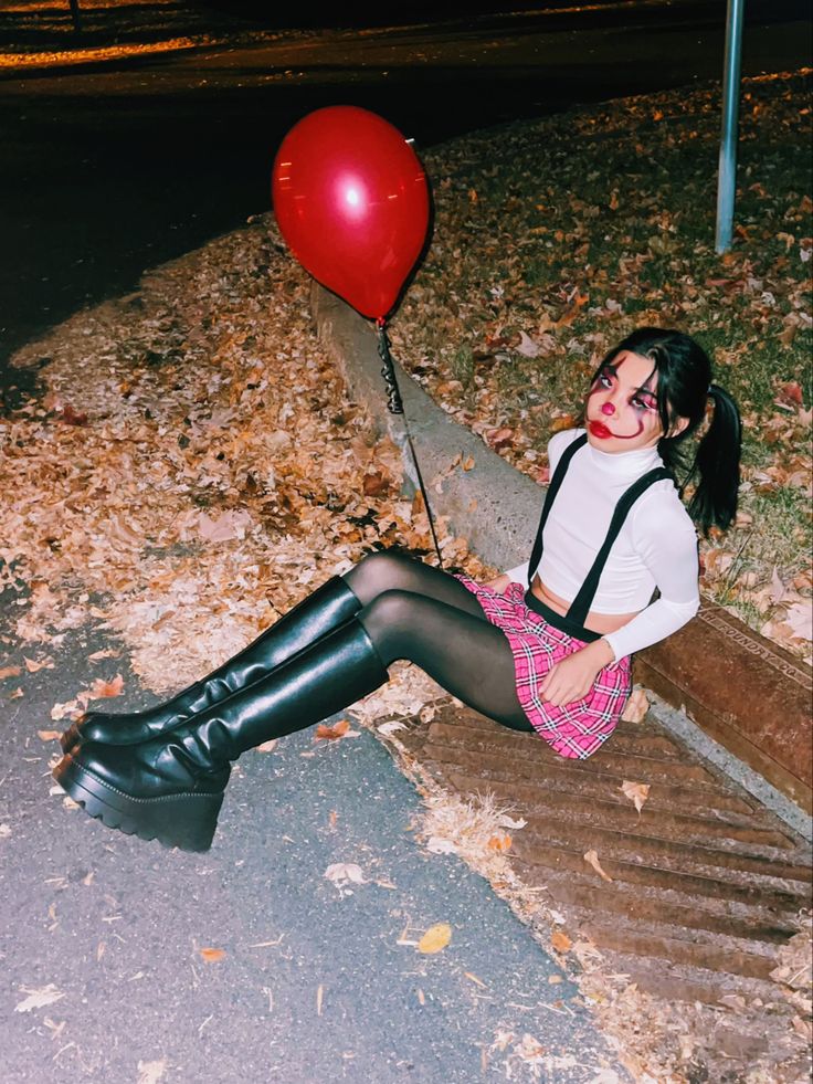 a woman sitting on the ground with a red balloon attached to her leg and wearing black boots