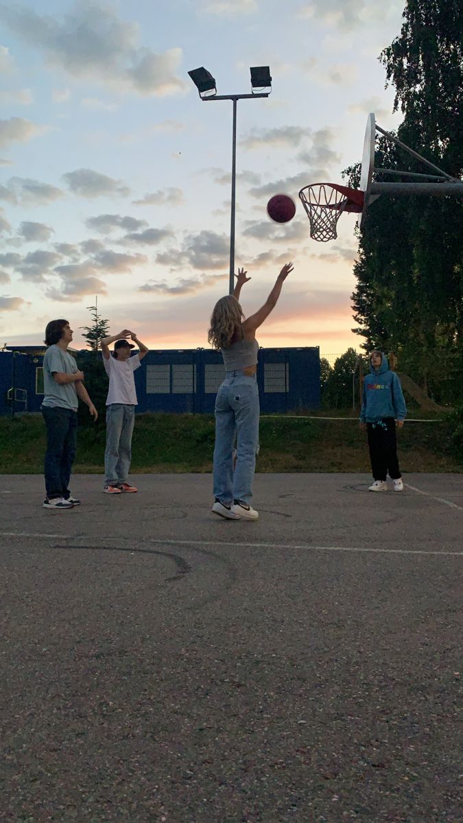 a group of people playing basketball on an asphalt court