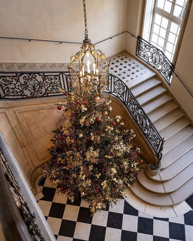 a chandelier hanging from the side of a staircase next to a christmas tree