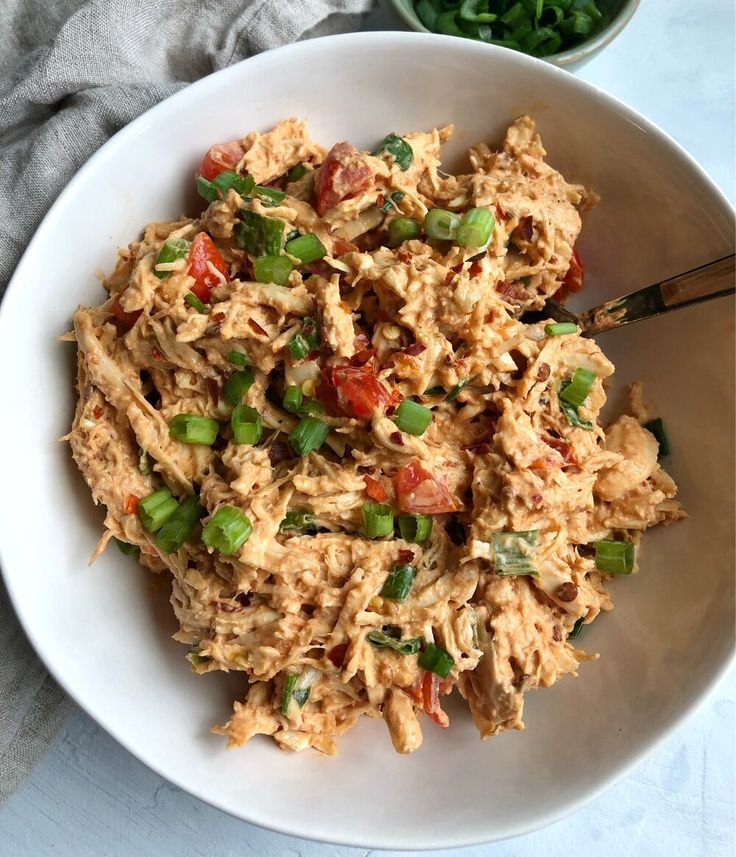 a white bowl filled with shredded chicken and veggies on top of a table