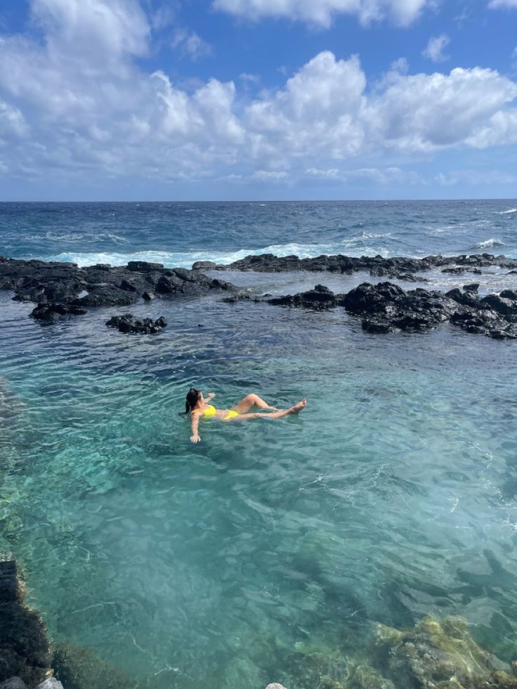 a woman swimming in the ocean near rocks