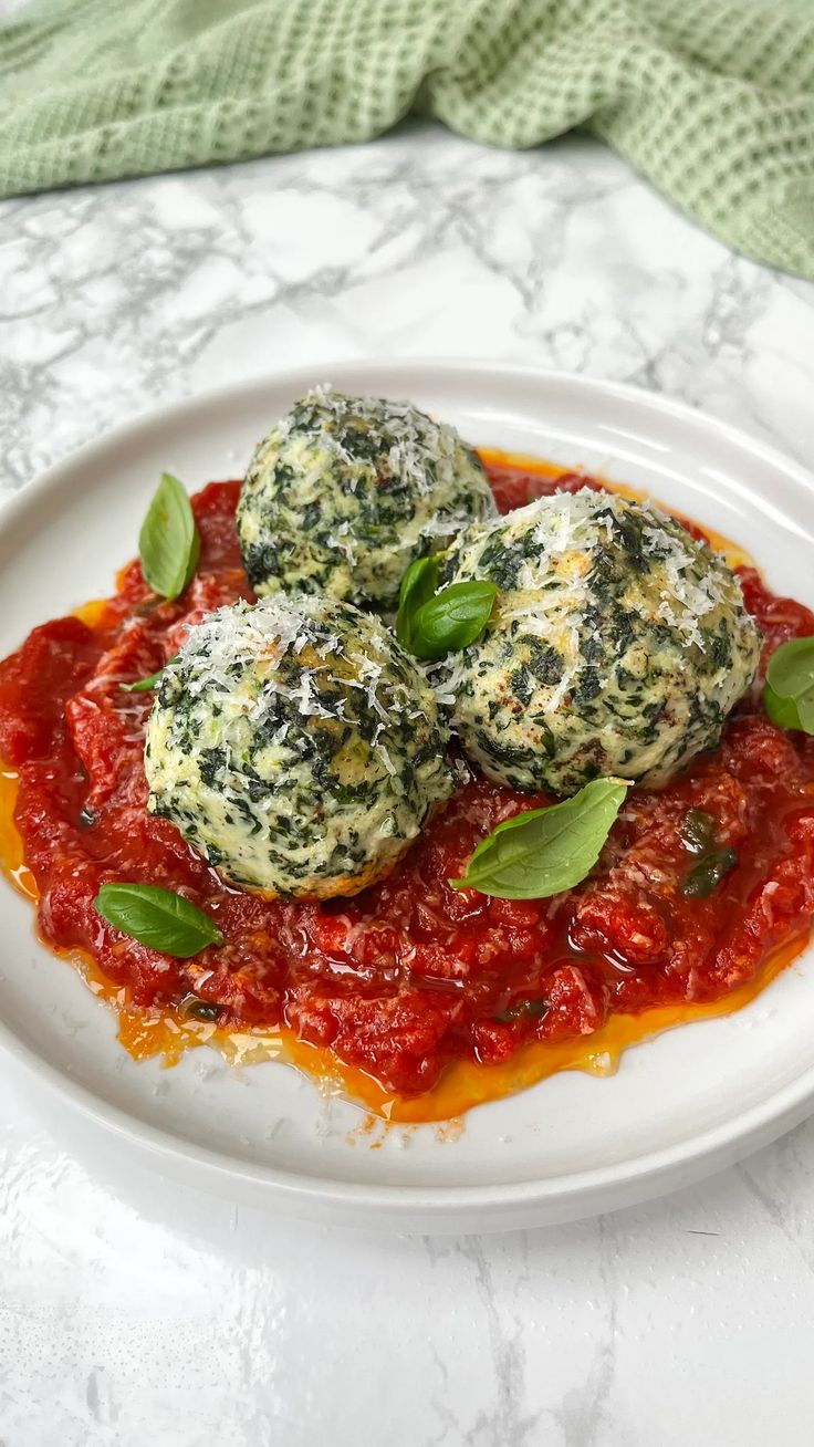 two ravioli with sauce and basil on a white plate