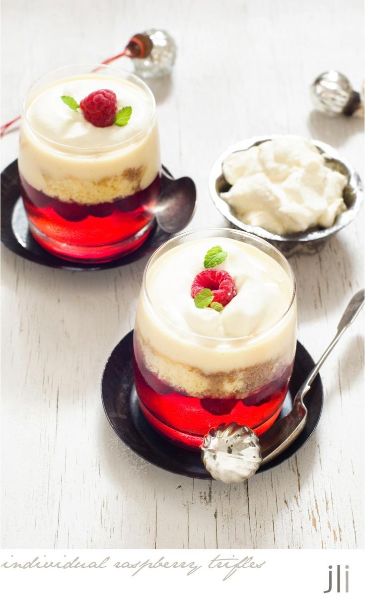 two desserts with raspberries and whipped cream in them on small black plates