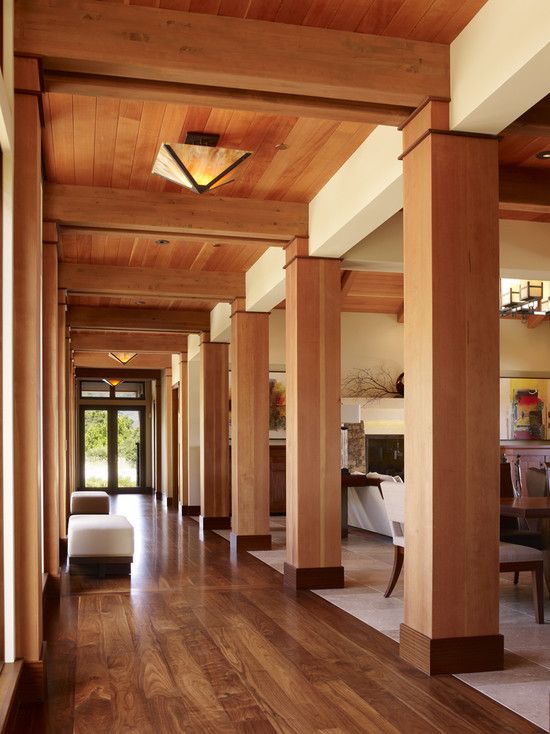 the hallway is lined with wooden columns and chairs, along with an open floor plan