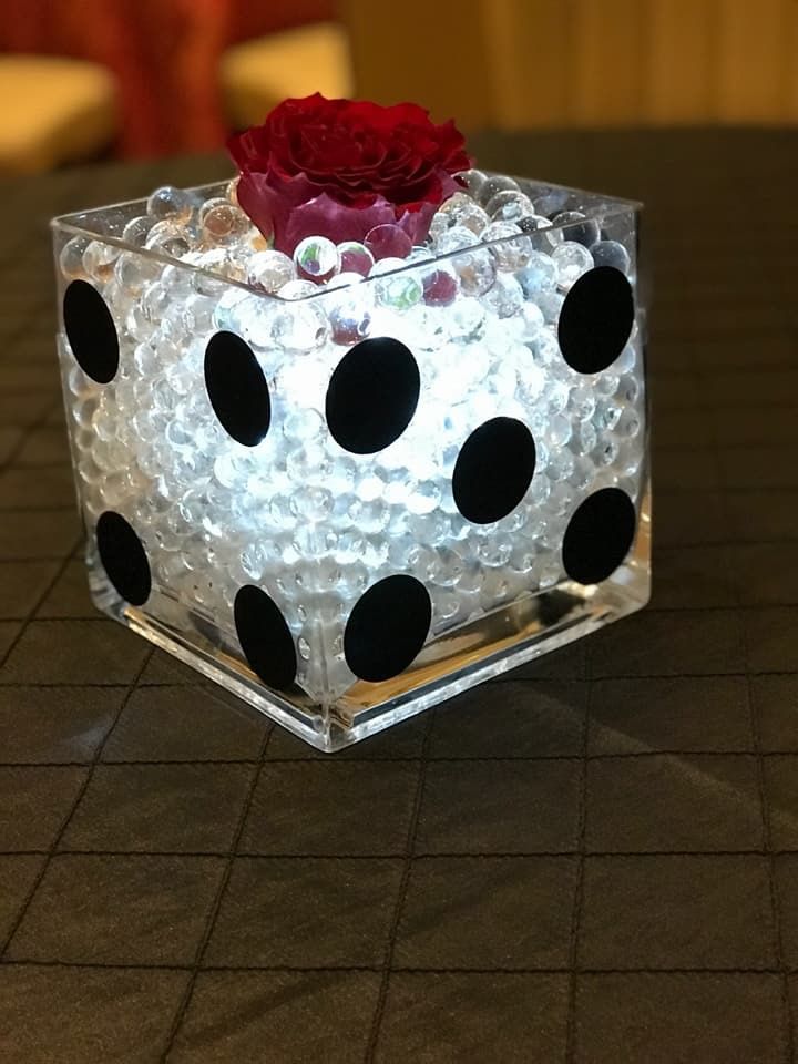 a glass block with black dots and a red rose in it sitting on a table