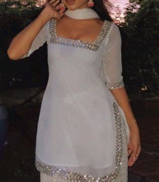 a woman wearing a white dress with silver sequins on the neck and sleeves