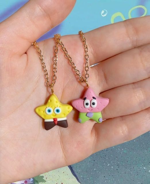 two cartoon characters are on a gold chain in the palm of someone's hand