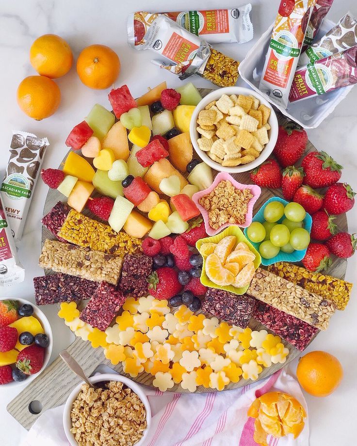 a platter filled with fruit, crackers, and other snacks on top of a table