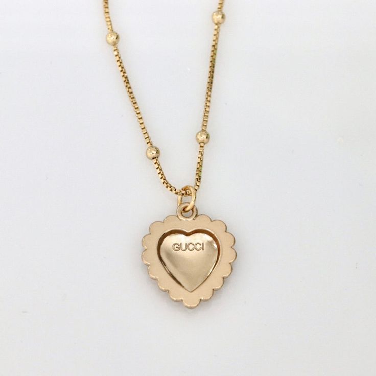 Stunning authentic Gucci heart-shaped pendant with classic interlocking GG logo in light champagne gold tone with elegant faux pearl detail. Product details: necklace length: 17.9 inches necklace material: 18k gold plated satellite chain pendant measurements: 20mm pendant is stamped "GUCCI" for authenticity Gold-tone Logo Plaque Pendant Necklace As Gift, Gift Necklace With Gold-tone Logo Pendant, Gold-tone Pendant Necklace As A Gift, Gold-tone Logo Plaque Pendant Necklace, Classic Gold-tone Logo Plaque Necklace, Elegant Gold-tone Logo Plaque Pendant Jewelry, Elegant Gold-tone Pendant Jewelry With Logo Plaque, Elegant Pendant Jewelry With Gold-tone Logo Plaque, Designer Necklace With Adjustable Chain For Gift