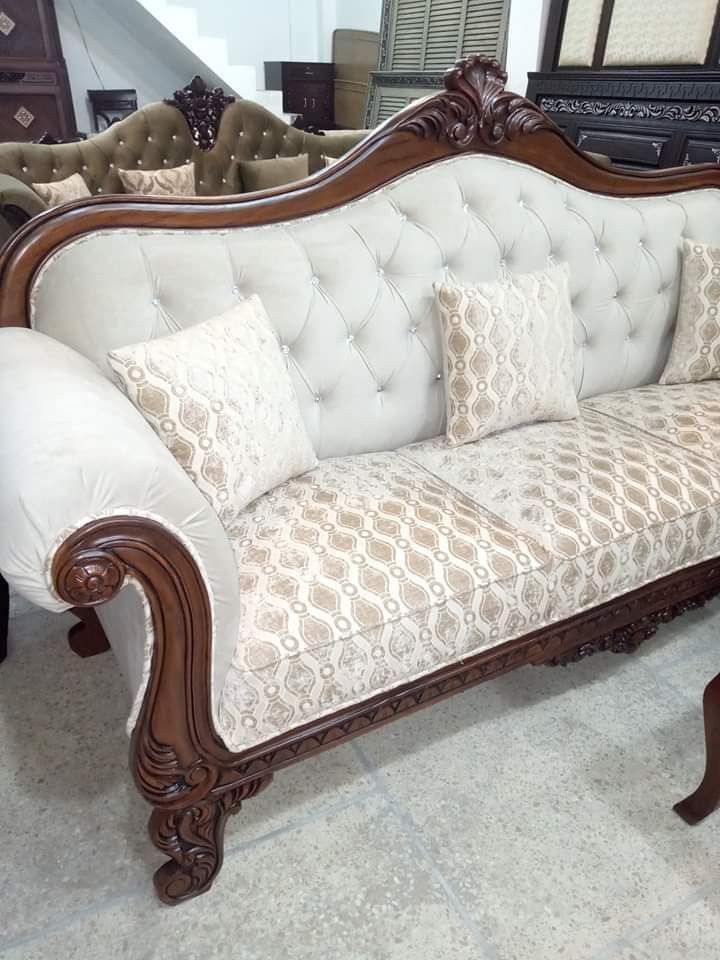 a white couch sitting on top of a floor next to a wooden table and chair