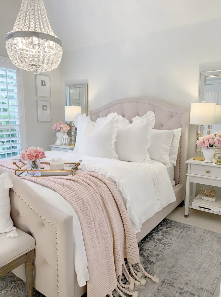 a white and pink bedroom with lots of pillows