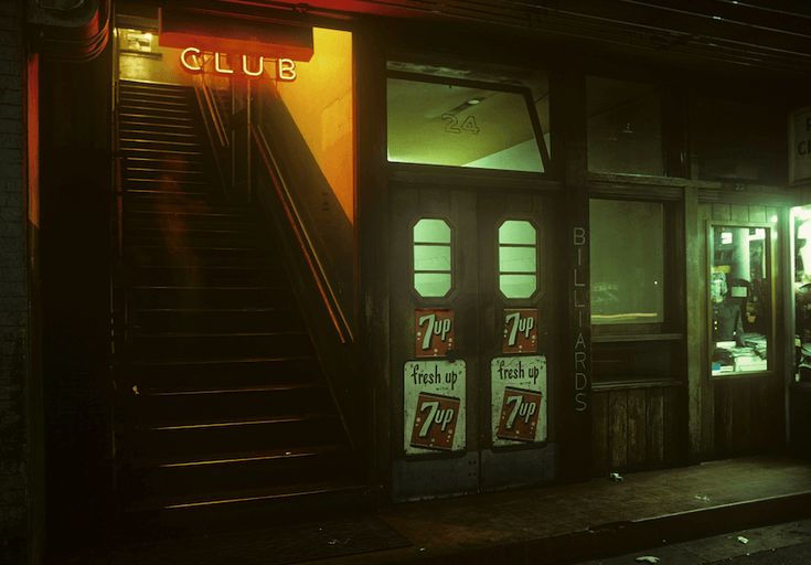 the entrance to a building with stairs leading up to it and lit by neon lights