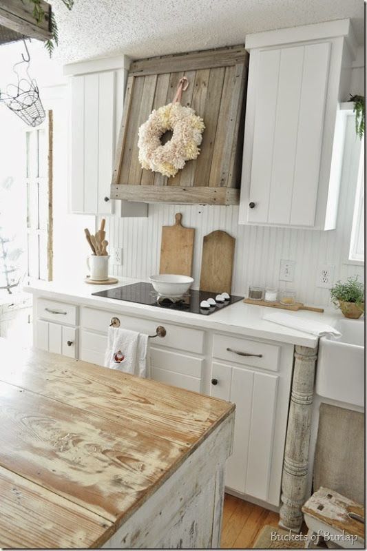 a kitchen with white cabinets and wooden counter tops, an old style stove top is hanging on the wall