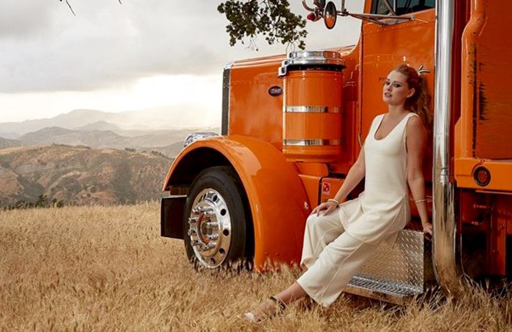 a woman sitting on the side of a large orange truck