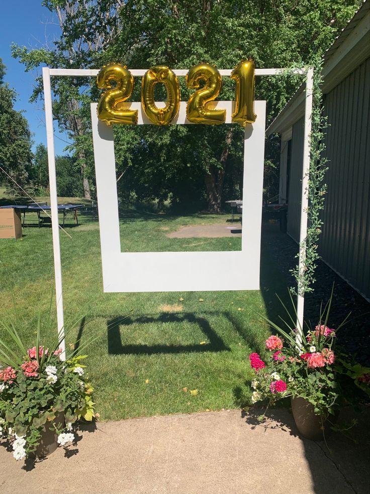 a white and gold photo frame with balloons in the shape of numbers on it sitting next to some flowers