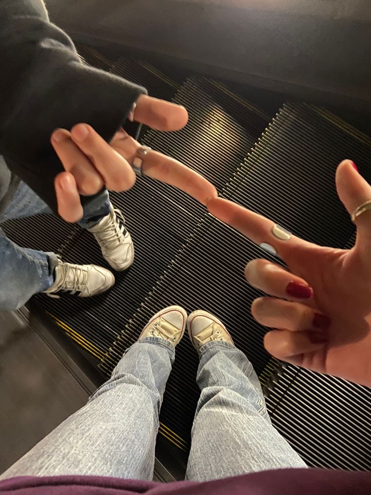 two people standing on an escalator with their hands extended out to touch each other