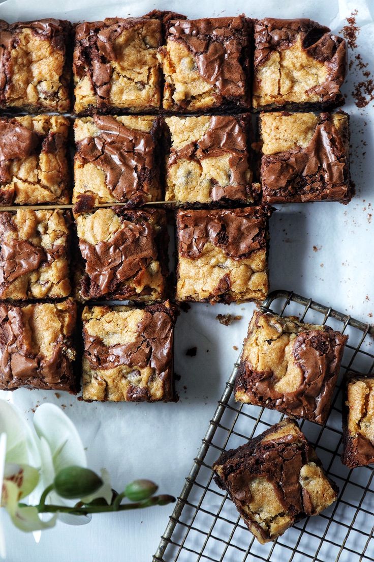 chocolate chip brownies cooling on a wire rack next to a white flower and some flowers