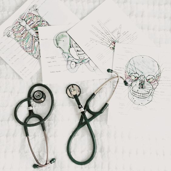 three medical stethoscopes sitting on top of paper with drawings behind them