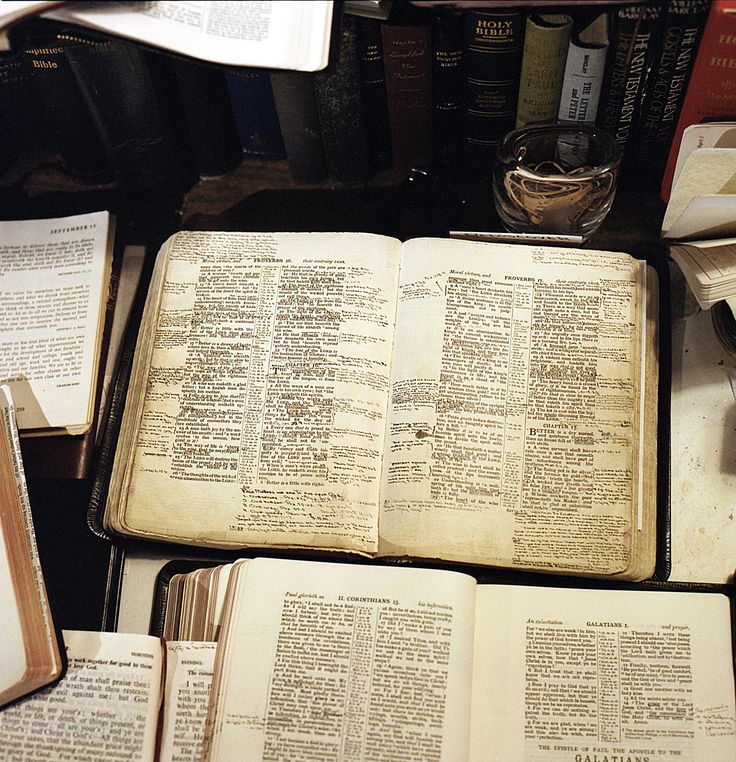 an open book sitting on top of a table next to many other books and papers