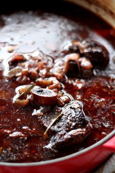 a red pot filled with stew and mushrooms