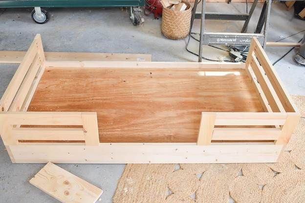 an unfinished bed frame sitting on top of a wooden floor next to other woodworking tools