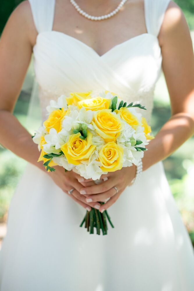 the bride is holding her yellow and white bouquet