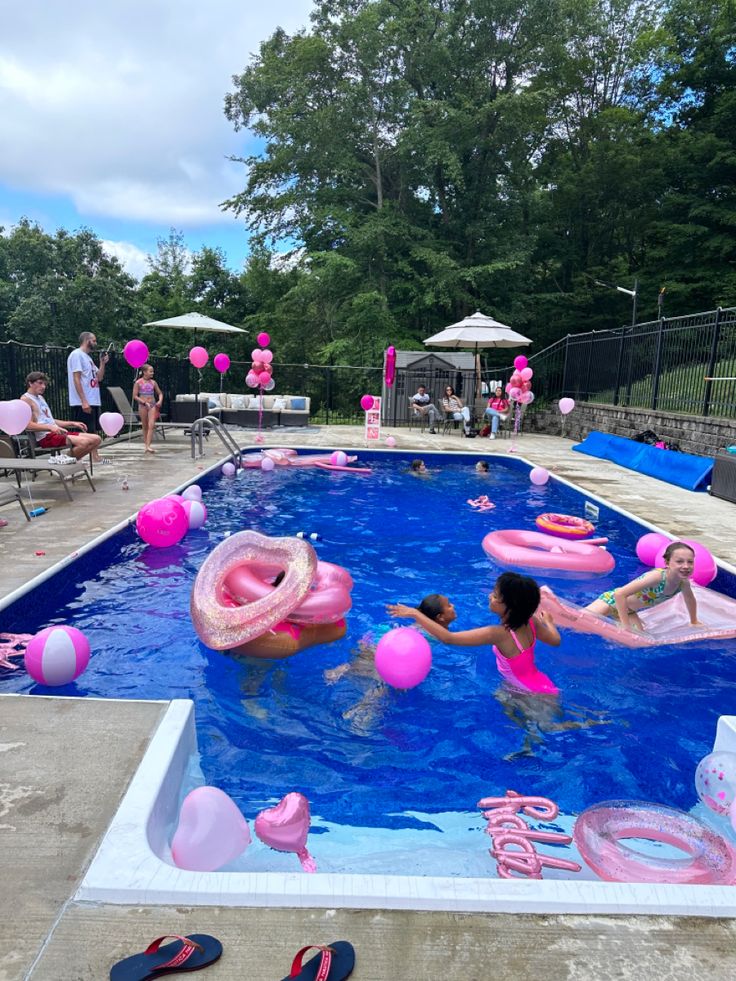 people are playing in the pool with pink floats and rafts on it's sides