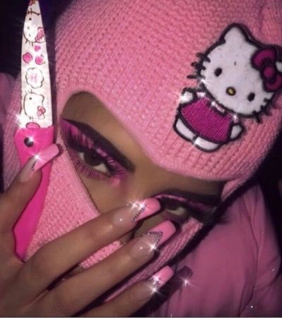 a woman with pink nail polish and hello kitty knitted hat holding up a pair of scissors