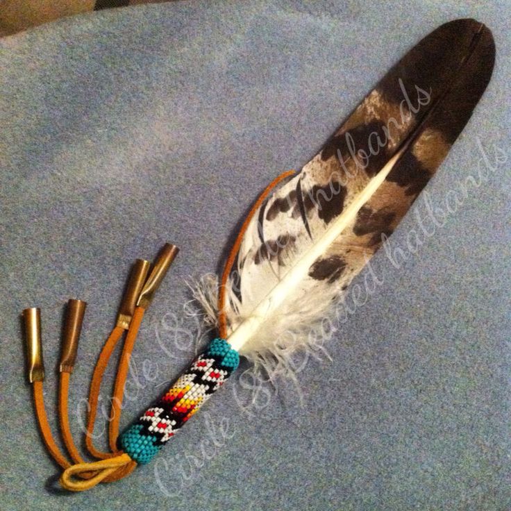 a feather with some beads on it sitting next to three other feathers and two brass - plated scissors