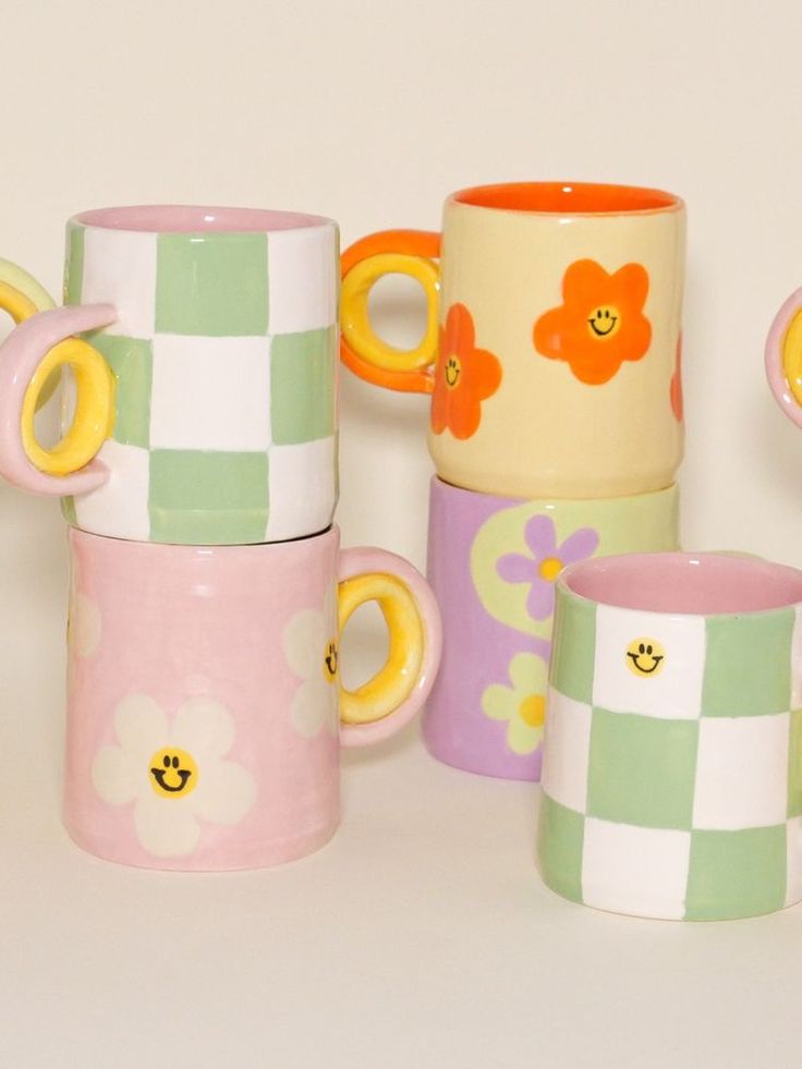 several different colored coffee mugs sitting next to each other on a white table top