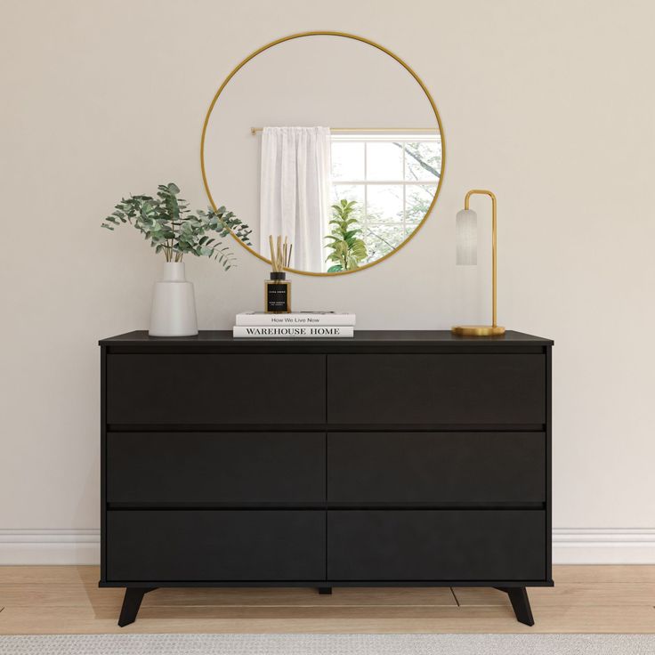 a black dresser with a mirror and plants on it in front of a white wall