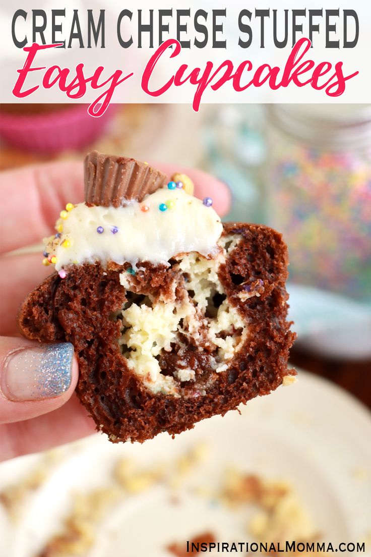 a hand holding up a chocolate cupcake with white frosting and sprinkles