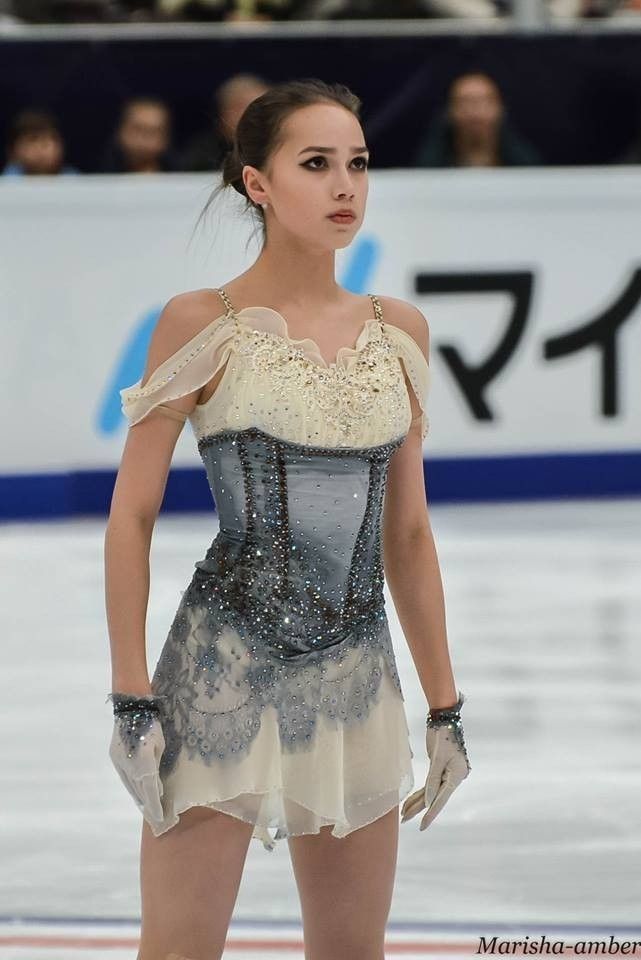 a female figure skating on an ice rink wearing a dress with lace and sequins