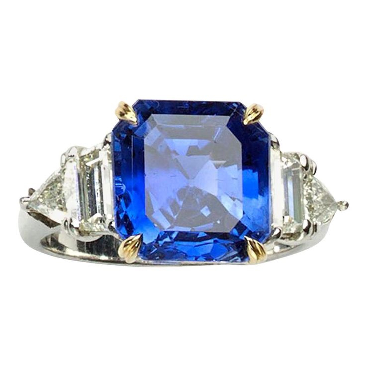 A Cartier sapphire and diamond ring, set with an emerald-cut, non heat treated Burma sapphire, with an estimated weight of 7.51 carats, in an 18ct yellow gold four claw setting, with shoulders set with a trapezoid and a trilliant-cut diamond on each side, weighing an estimated total of 1.60 carats, onto a polished shank, mounted in platinum, signed Cartier, numbered 802647, circa 2000, in its original Cartier box. Accompanied by GIA certificate 2173470219 and an I.A.J.A. Expertise certificate of Diamond Cluster Earrings, Platinum Earrings, Vintage Sapphire, Platinum Diamond Rings, Sapphire And Diamond Ring, Clover Earrings, Diamond Brooch, Diamond Cocktail Rings, Sapphire Pendant