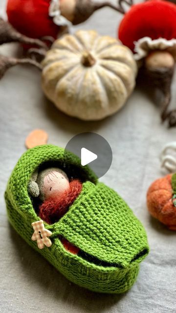 a knitted toy car with a small doll in it's hood sitting next to pumpkins