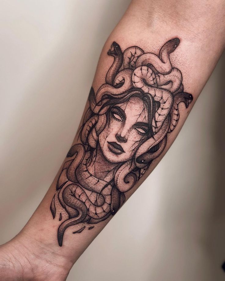 a woman's face and snake tattoo on the left arm, with black ink