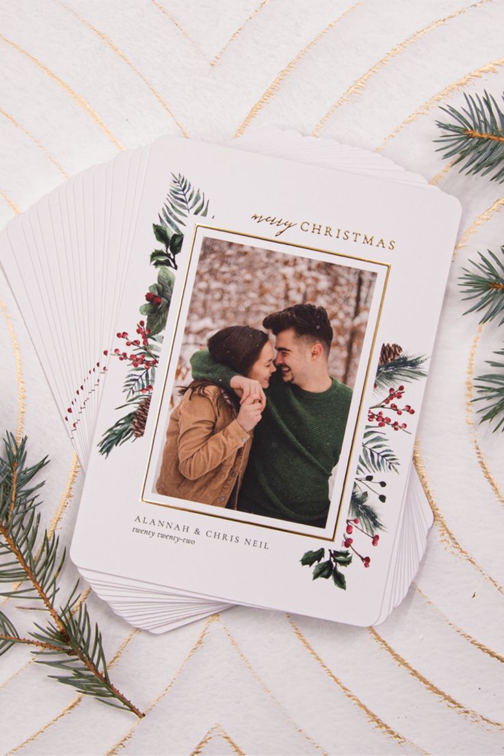 christmas cards with an image of a couple kissing on the cheek and evergreen leaves around them