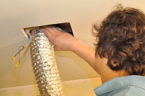 a woman is working on the ceiling in her home with some wires attached to it