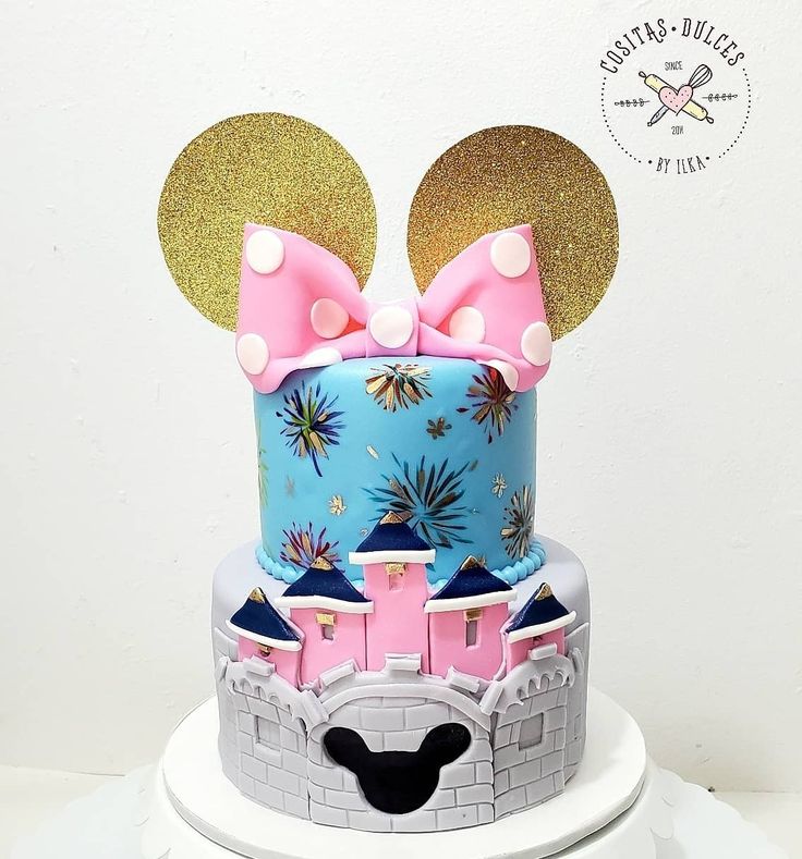 a birthday cake with minnie mouse ears on top and a castle in the middle is shown