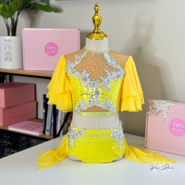 a yellow and white dress sitting on top of a table next to a pink box