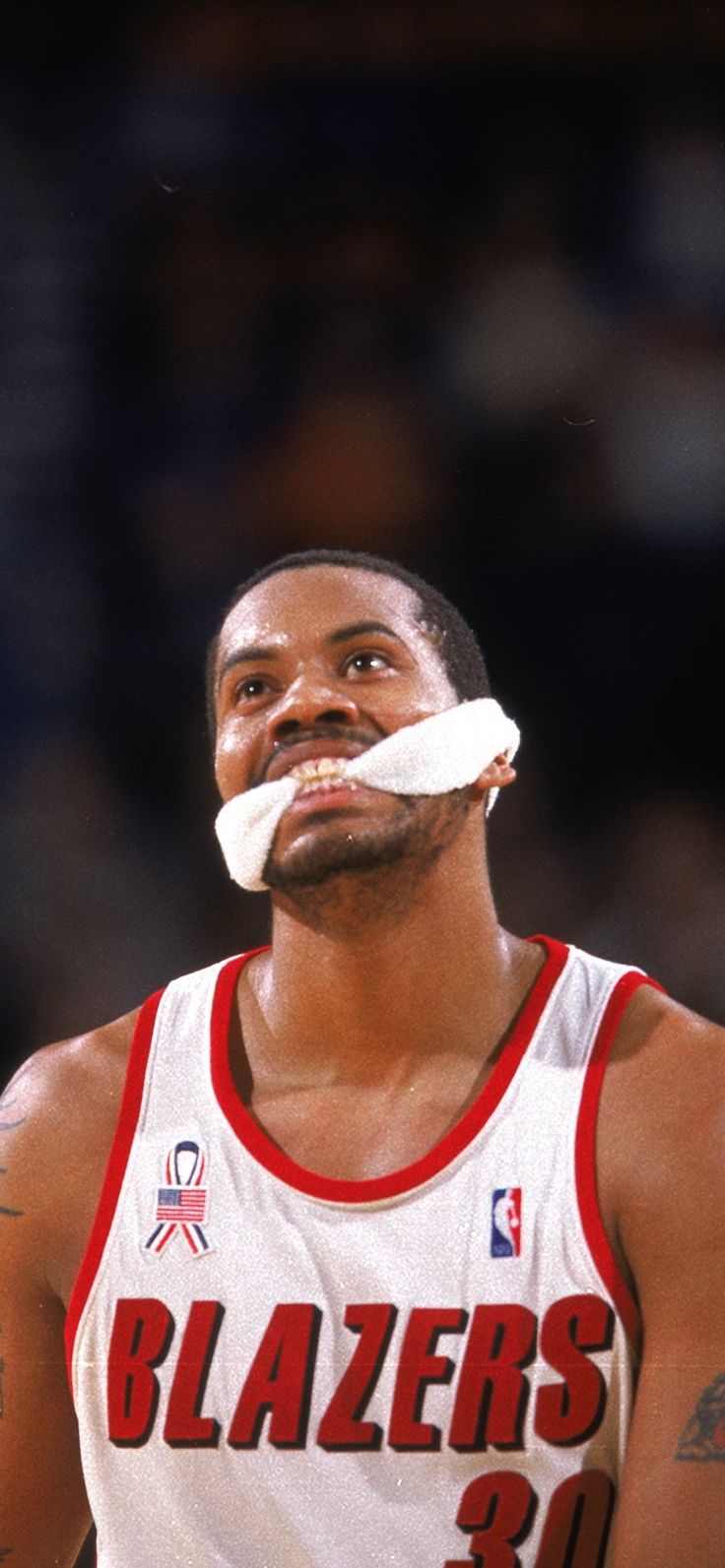 a close up of a basketball player with a piece of paper in his mouth and an injured eye