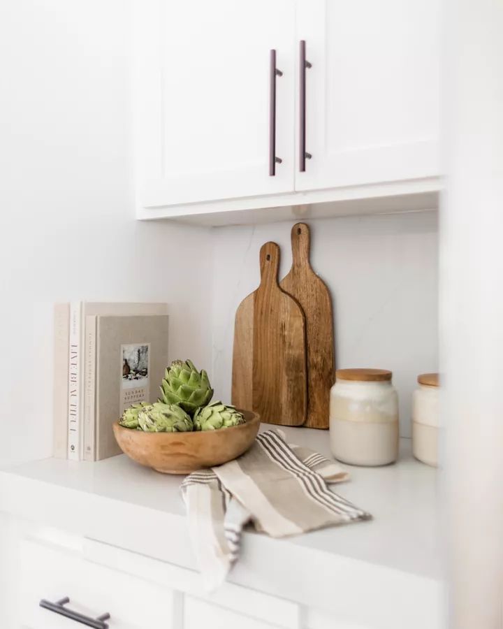 a wooden bowl filled with succulents on top of a white kitchen counter