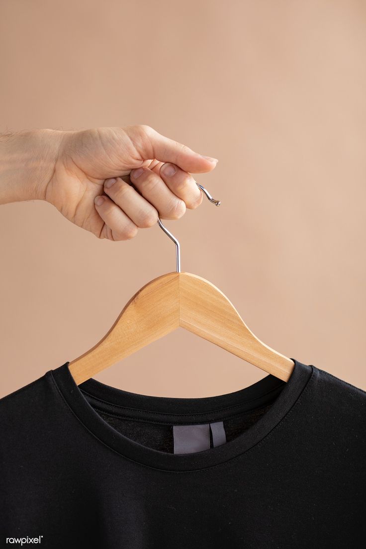 a person is holding a t - shirt on a hanger and pulling it up