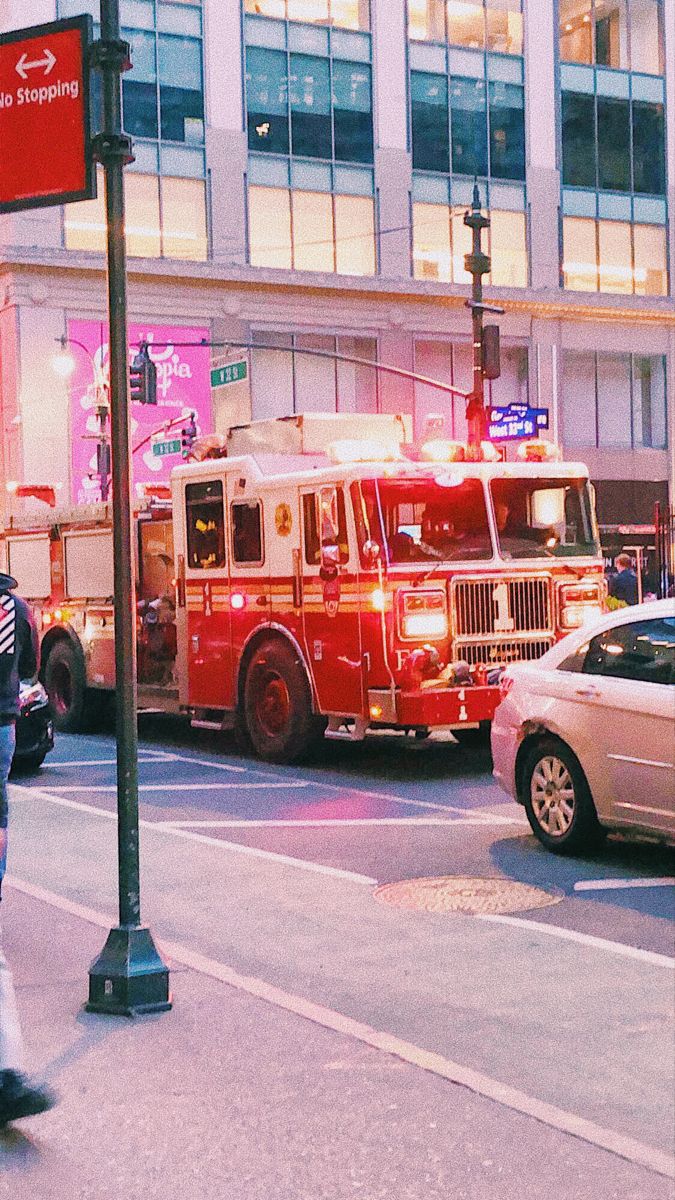 two firetrucks are parked on the side of the road in front of a tall building