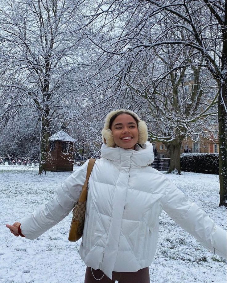 a woman is standing in the snow with her arms spread out and she's smiling