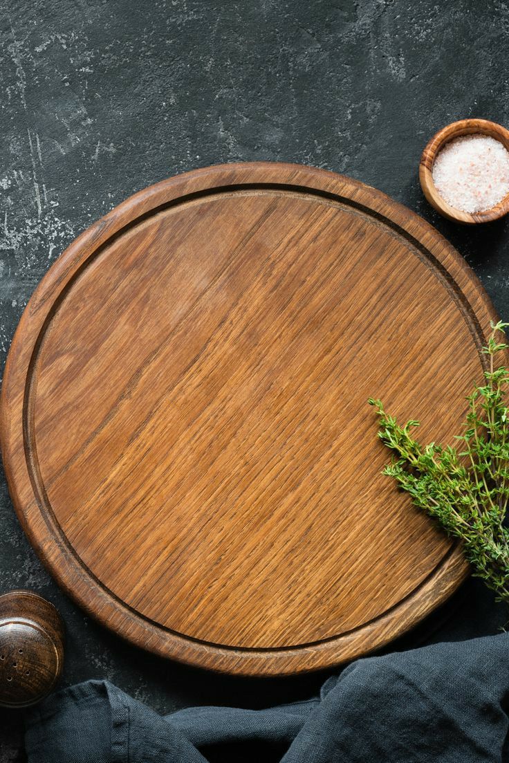 an overhead view of a wooden cutting board with herbs and salt on the side next to it